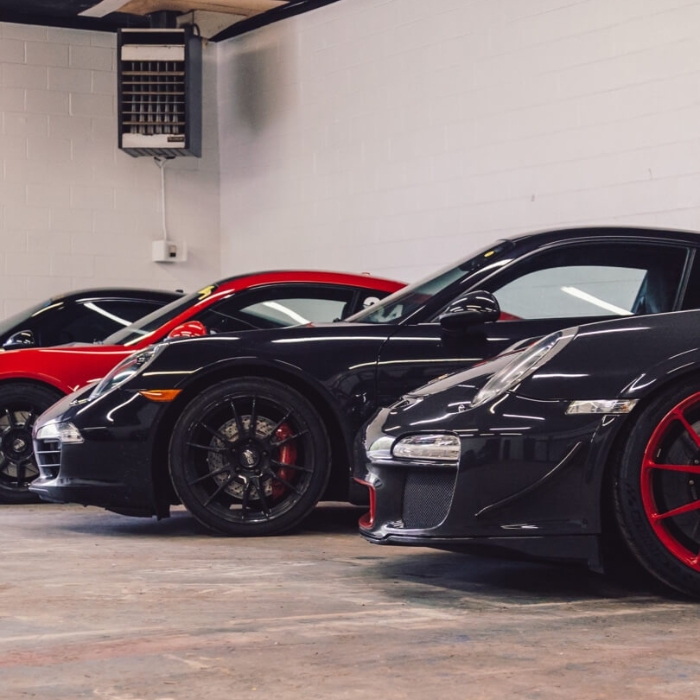 A lineup of several Porsche 911 sports cars parked inside a service garage.